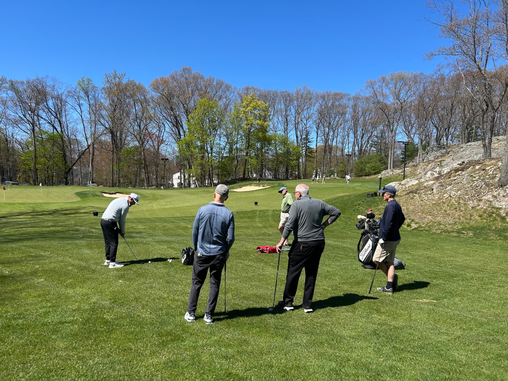 Adult golfers and coach on the KOHR practice green